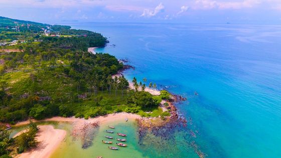 Stunning aerial view of a tropical island with lush greenery and crystal-clear ocean waters.