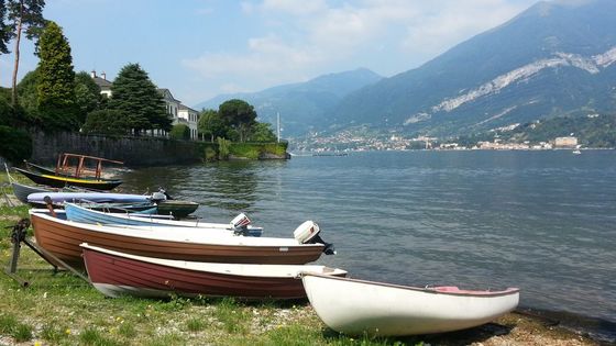 Peaceful view of boats on Lake Como in Bellagio, Italy with mountains in the background.